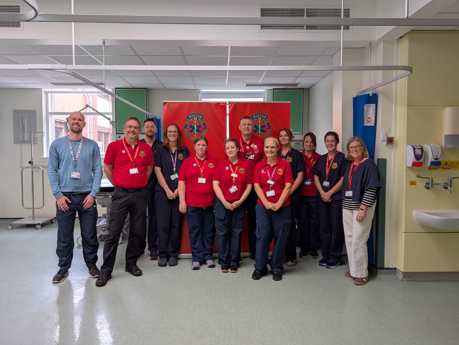 Team members from NISTAR pose on a hospital ward in front of NISTAR pop up banners