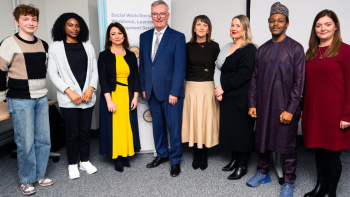 Social Work staff standing with Health Minister Mike Nesbitt at a professional event in front of a banner for Social Work Workforce Learning and Development Service.