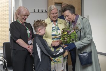 The Princess Royal is gifted a posy of flowers by a young boy.