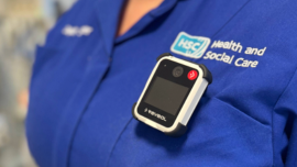 Body Worn Camera shown on a staff member wearing a bright blue tunic